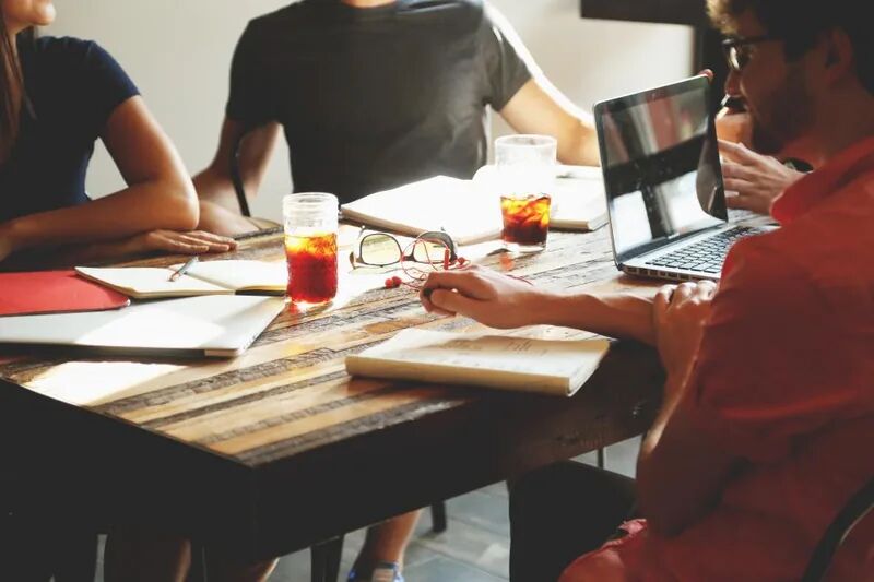 Small business team meeting around a table with laptops, representing new employee IT onboarding and offboarding