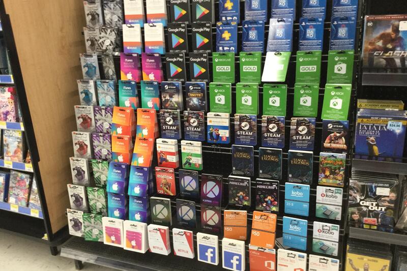 A store display rack filled with rows of gift cards for app stores, games, and streaming services, the kind of cards scammers ask victims to buy