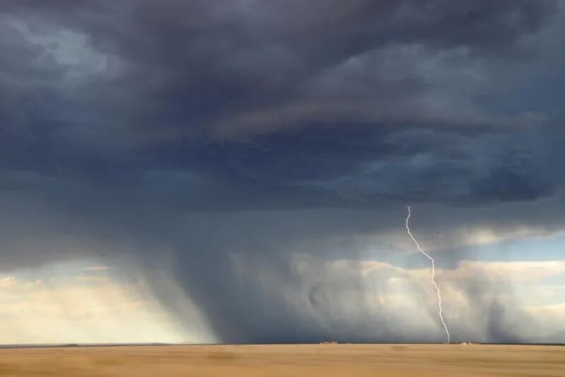 Monsoon thunderstorm with a lightning strike over open plains, showing the power surge risk to home and office electronics