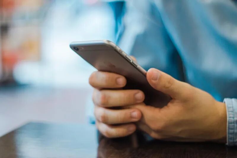 Person holding a smartphone to sign in, representing passkeys and phishing-resistant passwordless authentication
