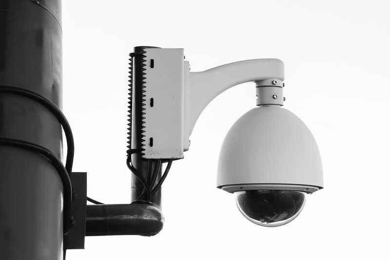 Wired PoE security camera mounted on a wall compared to a wireless camera, illustrating reliability differences for business surveillance