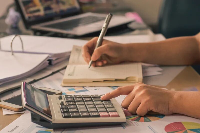 Person planning a budget with a calculator and notebook, representing year-end IT planning and technology budgeting for small business